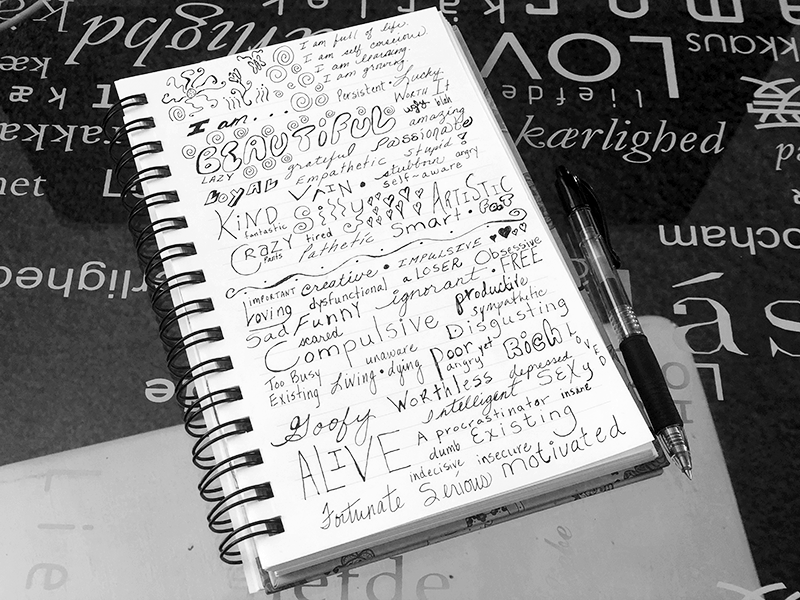 notebook on glass desk with i am affirmations handwritten on it